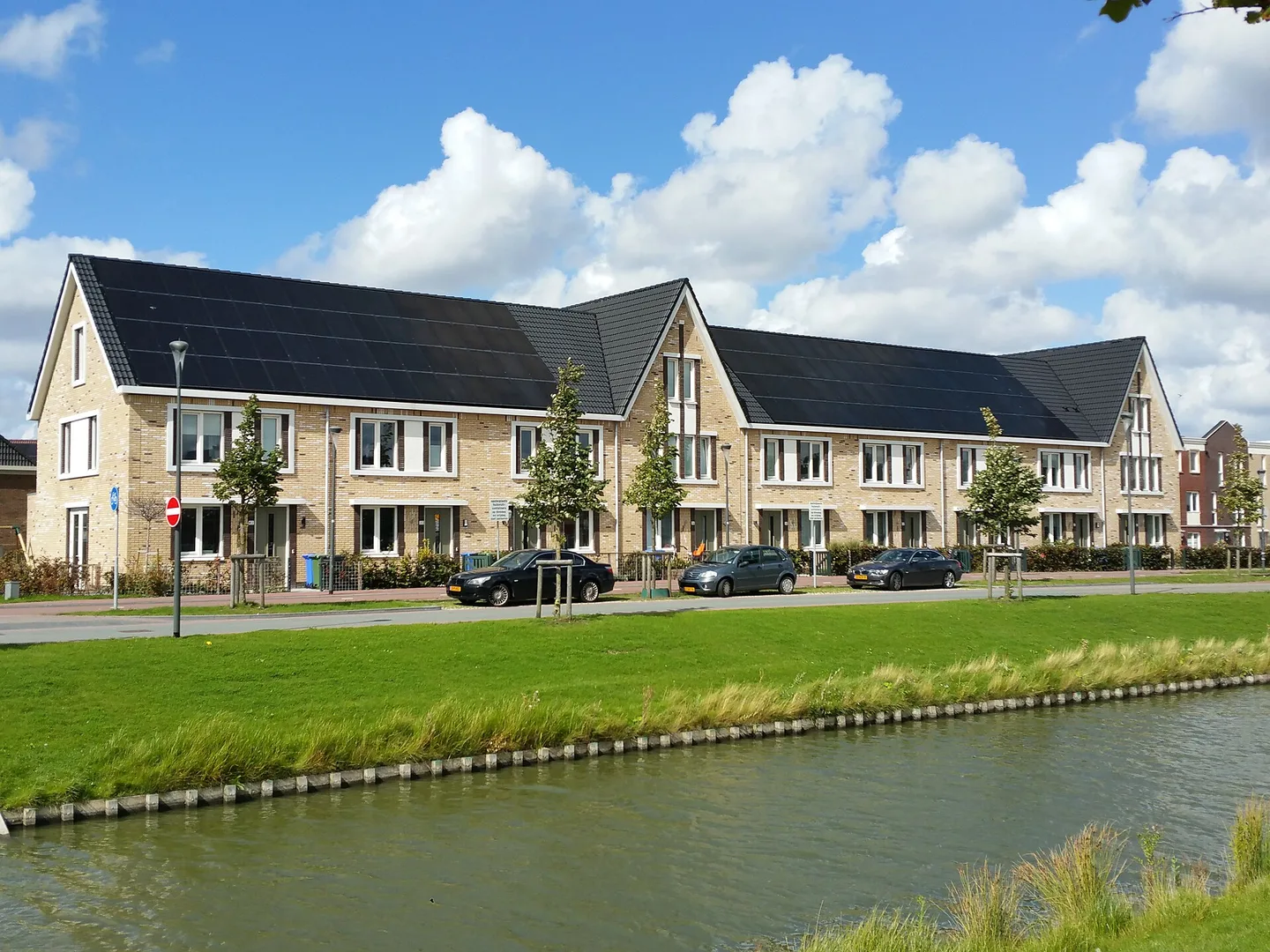 Nieuwbouwwoningen aan het water met zwarte zonnepanelen geïntegreerd in het dakvlak